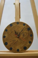 Tömör fa falióra epoxigyantával (23 cm), sötét kerek órajelölésekkel, fekete mutatókkal, fa állványon.