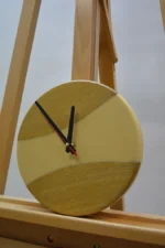 Tömör fa falióra epoxigyantával (23 cm) bézs színű gyanta berakással és fekete mutatókkal, fa állványon.