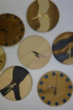 Különböző kézzel készített fa és epoxigyanta faliórák (23 cm) eltérő színekben és mintákkal.