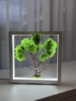 Zöld moha bonsai LED világítással világos asztalon.