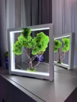 Zöld LED moha bonsai fehér fa keretben asztalon tükröződéssel.